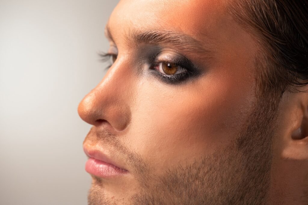 side view of part of face of serious young male fashion model with stage makeup